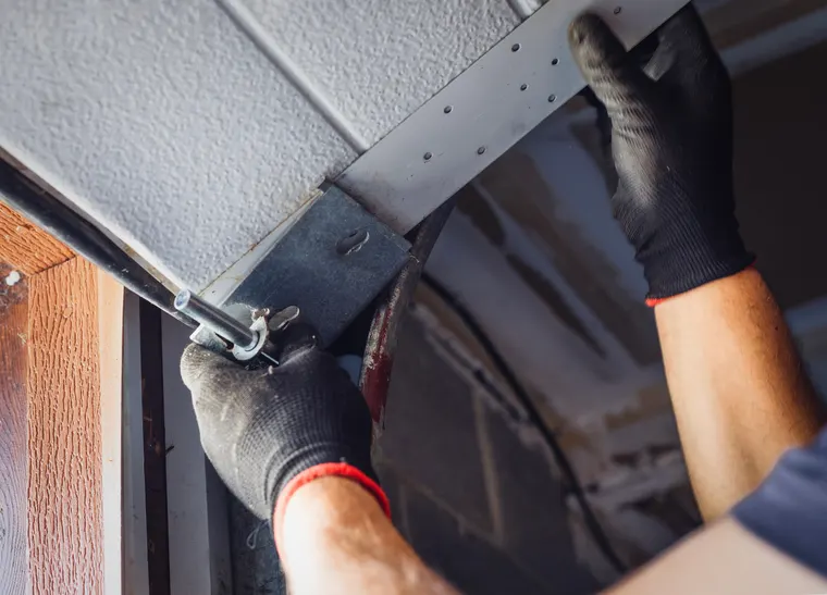 Garage door maintenance technician lubricating door hinges in San Diego