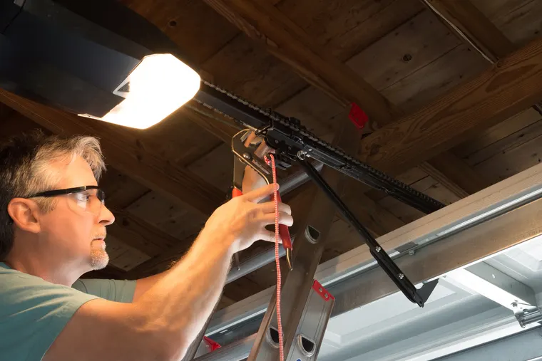 Garage door opener repair technician checking safety sensors in San Diego