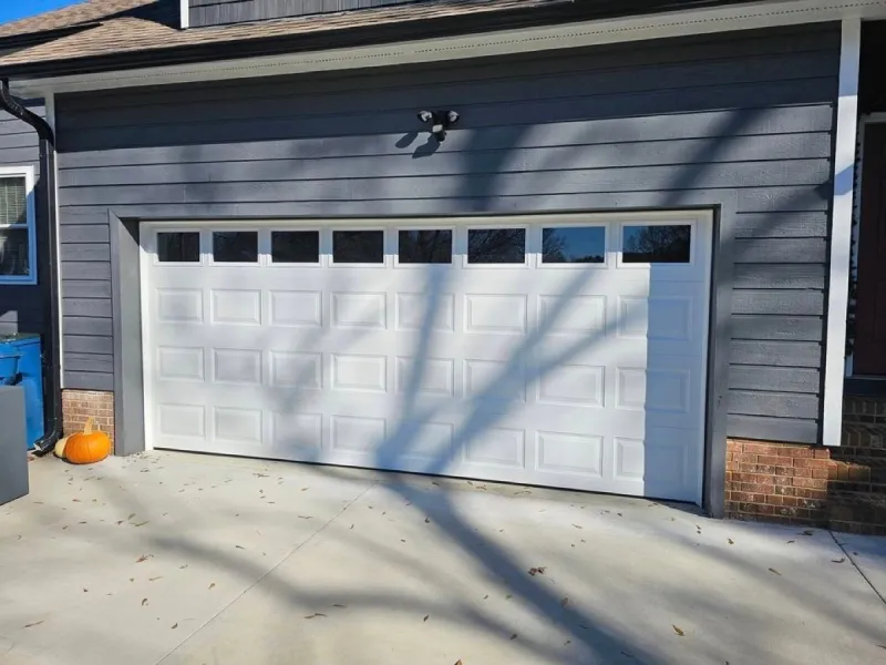 White raised panel garage door with windows on gray home