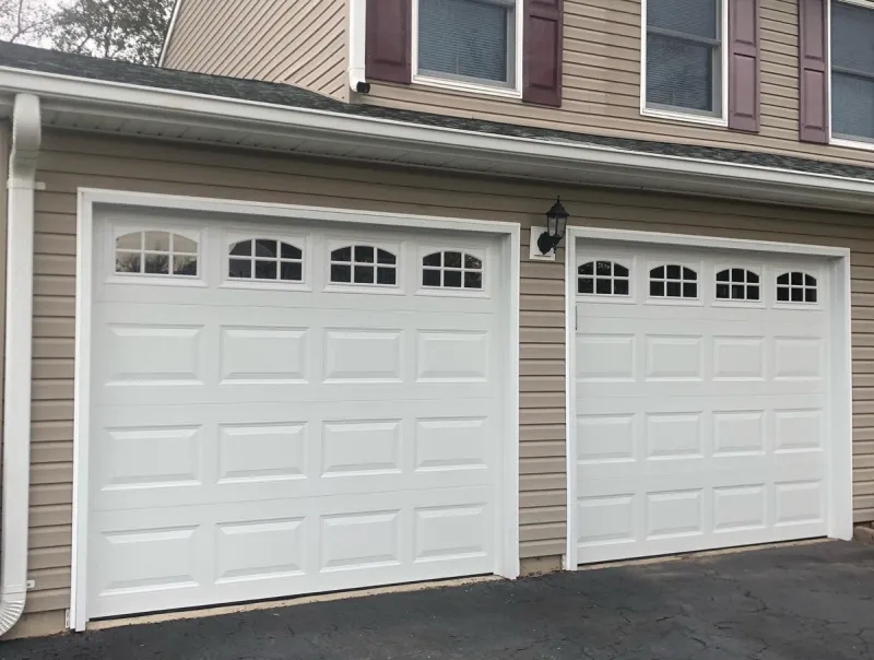 Double white garage doors with arched windows on two-story home