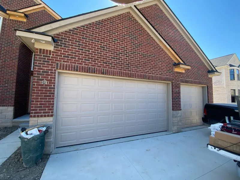 White raised panel garage doors on new brick construction