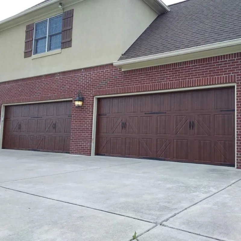 Carriage-style wood-tone garage doors on brick home