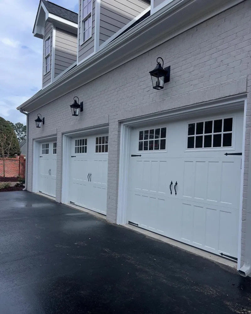 Three white carriage-style garage doors with decorative hardware